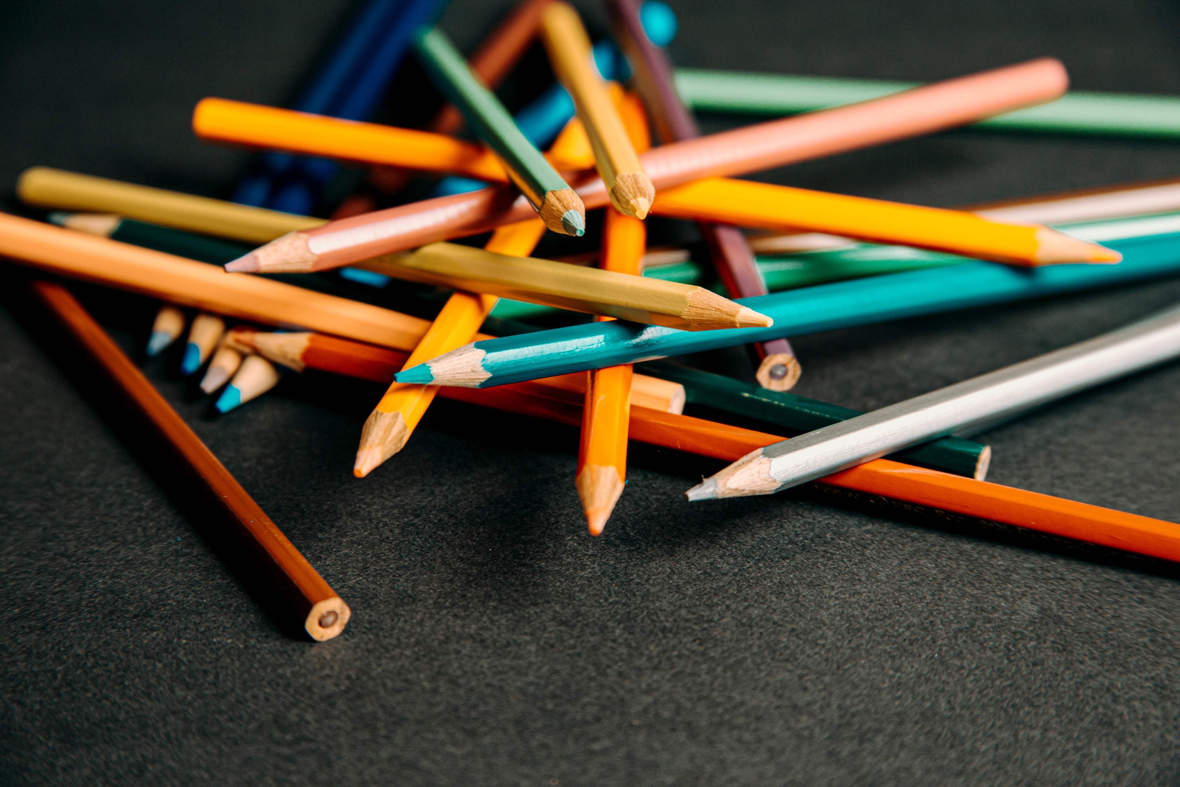 Colored pencils piled up on a black background
